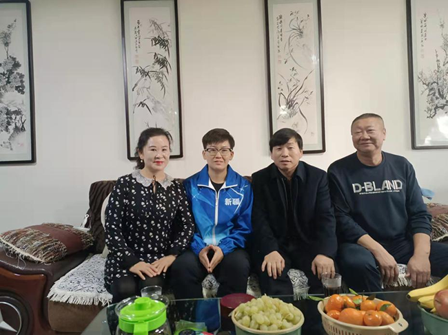 图为王明富在残疾人农户家中合影