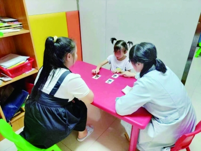 图为工作人员为孤独症儿童做康复训练