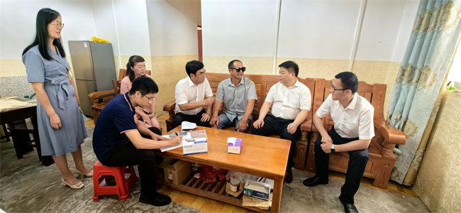 图为许健强到残疾边民家中慰问并送上免费配发的辅具