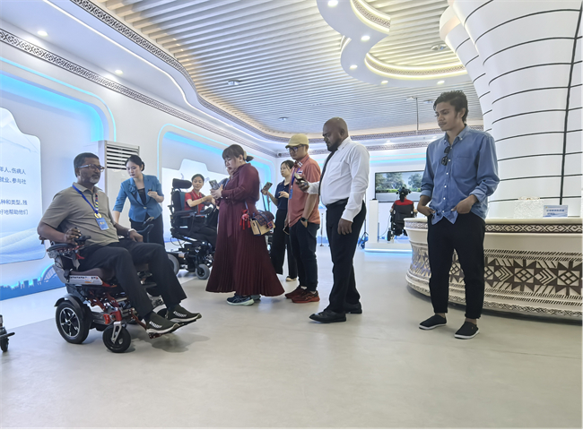 图为外国代表在辅具展示厅体验电动轮椅