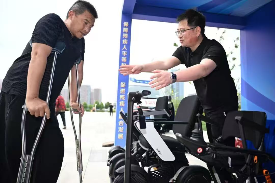 图为向残疾人介绍电动轮椅等辅助器材
